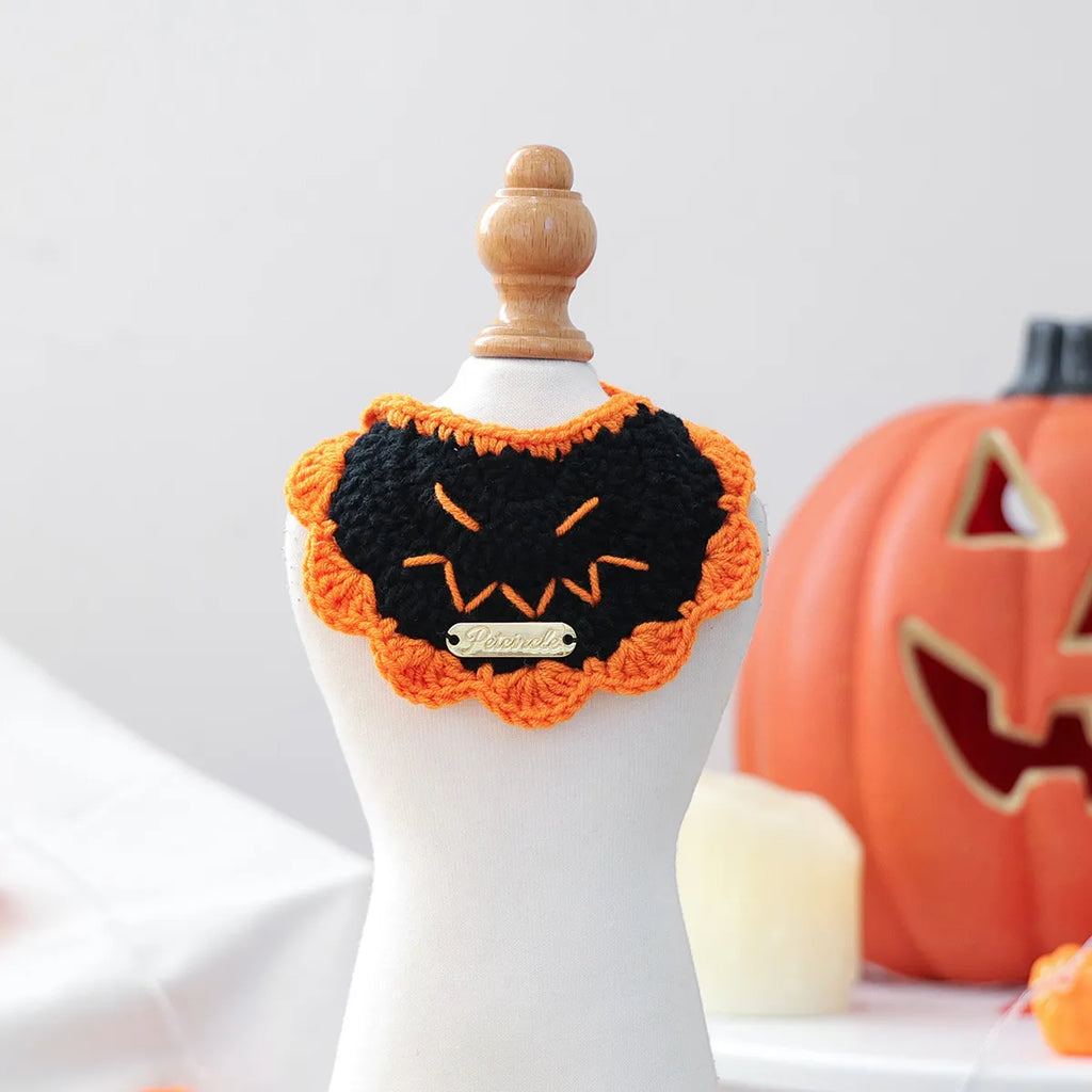 Pet wearing black pumpkin gold-label yarn bib, Halloween festive look.

