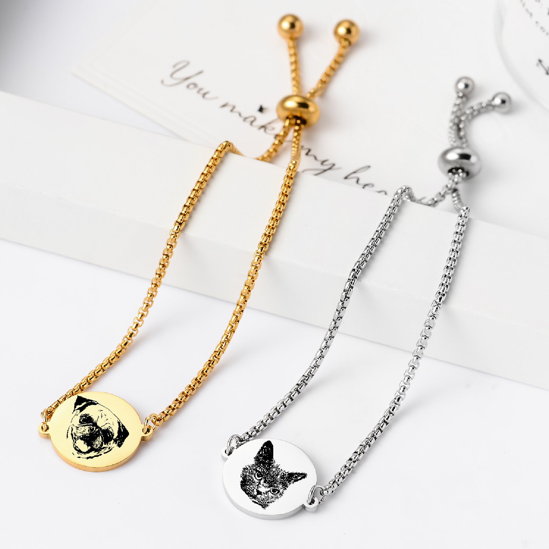 Long display of multiple pet face bracelets with gold and silver pendants.
