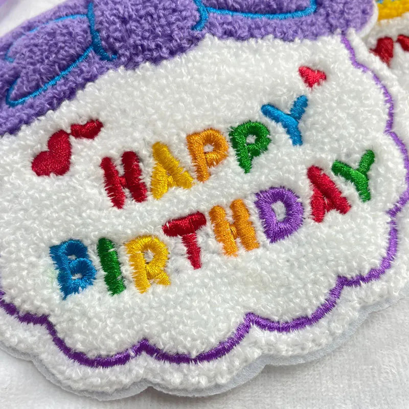 Close-up view of purple birthday bib with “Happy Birthday”