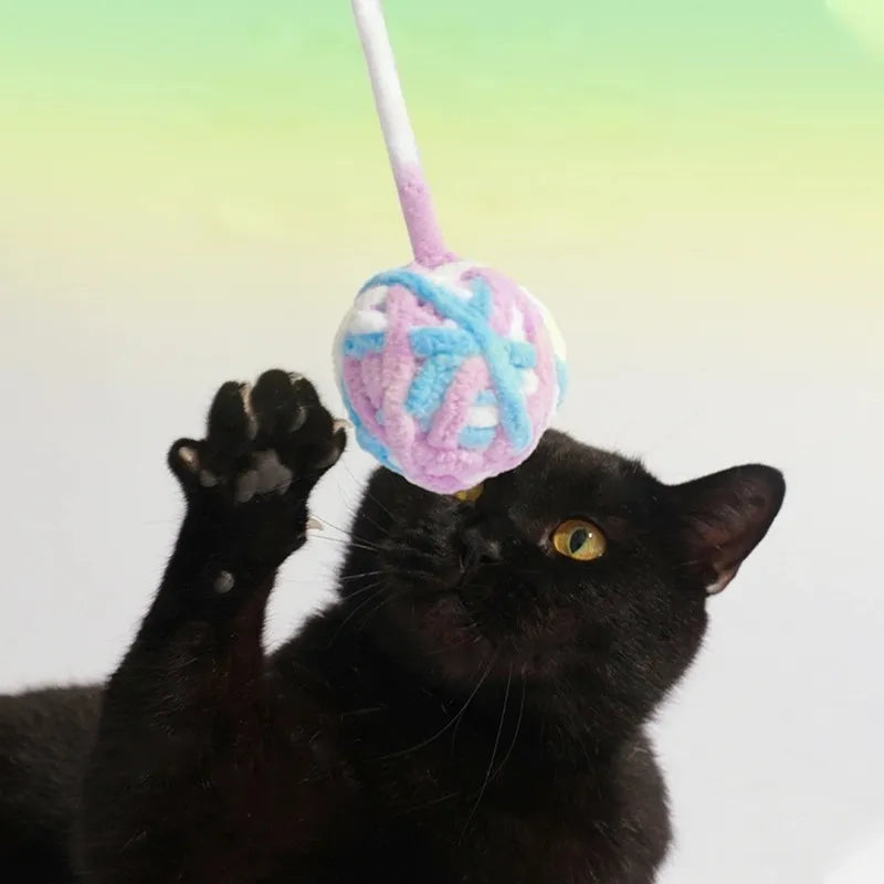 Cat hitting hanging egg-shaped yarn ball toy