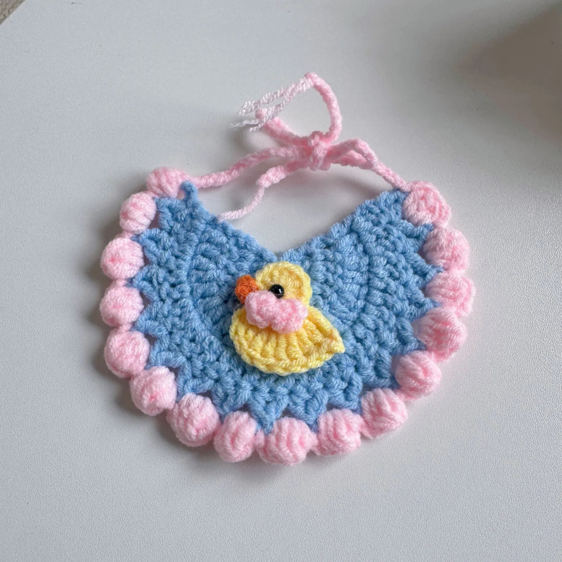 Yellow pet bib with duckling design and pink pom-poms